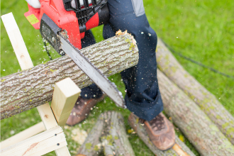 Homme utilisant une tronçonneuse thermique pour couper du bois de chauffage